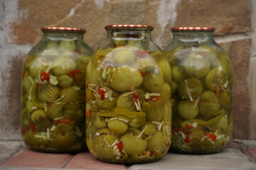 Three cans of green canned green tomatoes on a stone background.