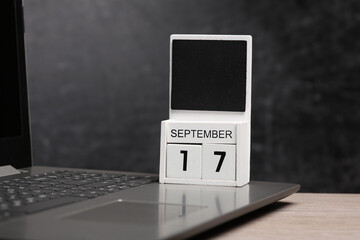 Calendar with september 17 date and laptop on table against chalk board background