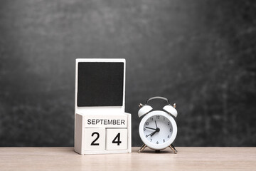 Wooden Calendar with september 24 date and alarm clock on table against chalk board background