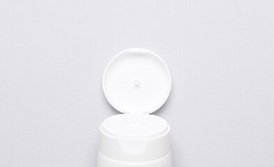 Open cream tube part on gray background. Top view