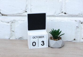 October 03 wooden calendar date with plant on table against brick wall background. Deadline, planning, business concept