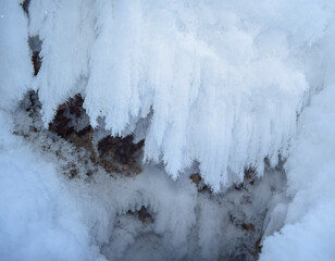 Near a small cave, ice crystals form in the form of chains due to high humidity