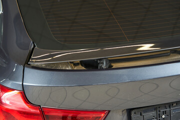 rising rear spoiler wing of a gray car. wing lifting mechanism.