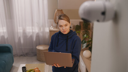 Caucasian woman installs security camera. Woman sets up angle of CCTV camera at home and rotates it...