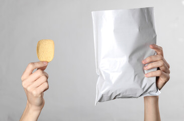 Female hands holding mock up pack of chips on gray background. Template for design