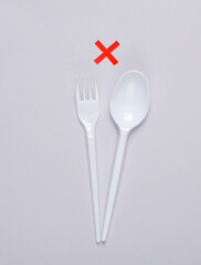 Plastic fork with spoon and rejected sign on gray background. Eco concept