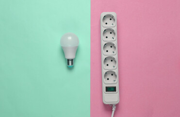 Electrical Extension cord and light bulb on pink blue background.