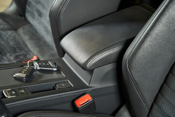 Fototapeta na wymiar car seat side support, gray center armrest, keys lying on the center console and seat belt buckle