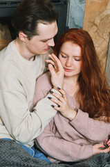 Lovely couple near the fireplace at home. A boy kisses a girl
