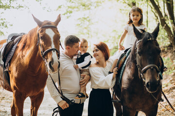 Fototapeta premium Young family with kids having fun with horse in forest