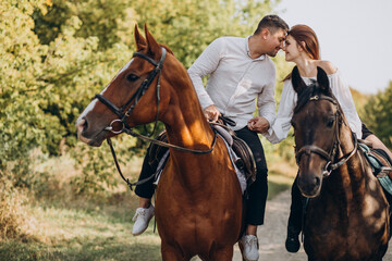 Young couple riding horses together in park