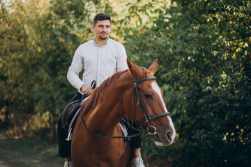 Handsome man riding a horse in forest