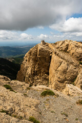imagen de una casa de vigilancia en la punta de la montaña de roca, con el cielo azul lleno de nubes 