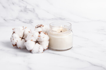 Handmade scented candle in a glass and cotton flowers. Soy or coconut wax candle