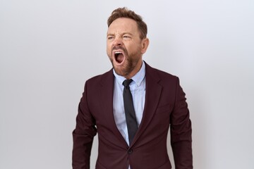 Middle age business man with beard wearing suit and tie angry and mad screaming frustrated and furious, shouting with anger. rage and aggressive concept.