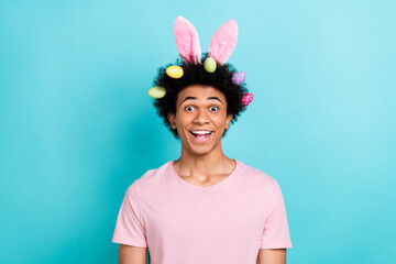 Photo portrait of crazy amazed young student guy funky chevelure hairdo wear easter bunny pink ears colorful eggs isolated on aquamarine background