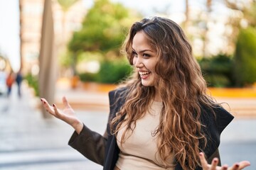 Young beautiful hispanic woman smiling confident speaking at street