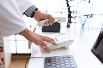 Young hispanic man pharmacist calling on telephone at pharmacy