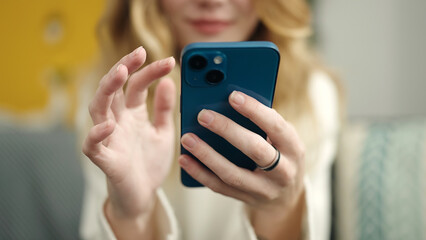 Young blonde woman using smartphone at home
