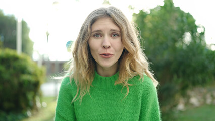 Young blonde woman smiling confident speaking at park