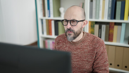 Young bald man student using computer studying at university classroom