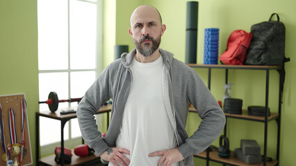 Young bald man standing with relaxed expression at sport center