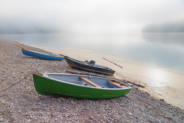morning scenery at lake Sylvensteinsee, gravel beach with rowing boats. foggy sky with copy space
