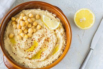 Home made hummus bowl, decorated with boiled chickpeas, olive oil, lemon on a light background. Top View.
