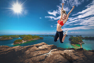 girl jumping o a rock in front of a tropical see during a sunshine day