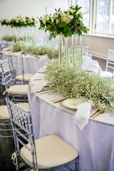 Fototapeta premium Event table setting with wine glasses, acrylic flower stands, baby's breath and candles on S curve table.