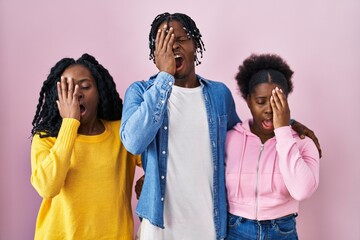 Group of three young black people standing together over pink background yawning tired covering...