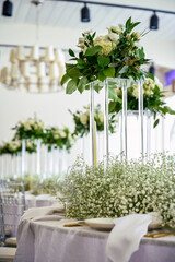 Event table setting with wine glasses, acrylic flower stands, baby's breath and candles on S curve table.