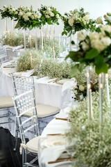 Event table setting with wine glasses, acrylic flower stands, baby's breath and candles on S curve table.