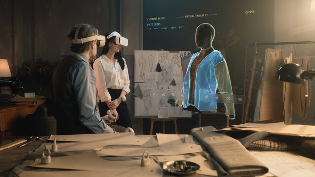 Tailor and female customer put VR goggles in atelier workshop. 3D hologram of jacket pattern. Virtual interface menu of program for designing and modeling clothes. Technologies of augmented reality.