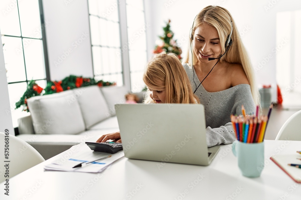 Poster Mother and daughter teleworking sitting by christmas tree at home