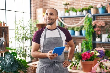 Young latin man florist smiling confident using touchpad at flower shop