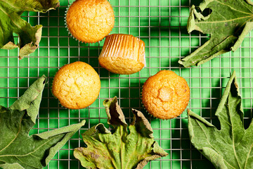 Vanilla Caramel Nuts Muffins In Paper Cups and maple leaves On green fence background