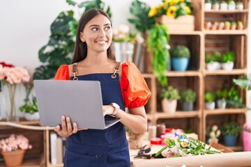 Fototapeta premium Young beautiful hispanic woman florist smiling confident using laptop at florist