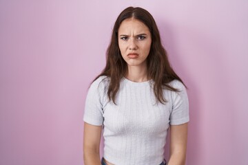 Fototapeta premium Young hispanic girl standing over pink background skeptic and nervous, frowning upset because of problem. negative person.