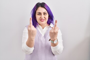 Plus size woman wit purple hair standing over white background showing middle finger doing fuck you...