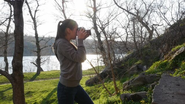 Girl with a professional camera in nature. Holds a camera and takes pictures of nature.