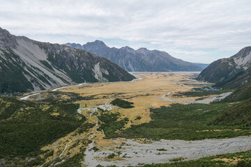 Fototapeta na wymiar Mount Cook Nationalpark von oben mit Wäldern, Wiesen, Flüssen und bergen bei wolkigem Himmel.