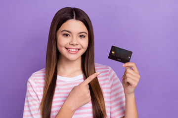 Photo of adorable cute girl dressed striped t-shirt pointing finger bank card isolated purple color background