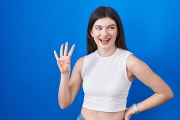 Fototapeta na wymiar Young caucasian woman standing over blue background showing and pointing up with fingers number four while smiling confident and happy.