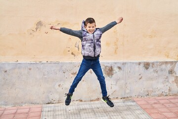 Blond child smiling confident jumping at street