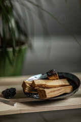 magic smoke from a burning palo santo stick lying on a natural shell incense stand on a wooden shelf in the interior Concept of mental health