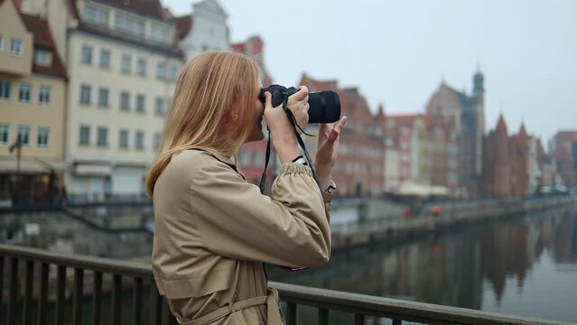 Close up portrait of cheerful beautiful female in good mood with camera standing outdoors in city. Happy pretty young woman tourist taking photo. Photographer taking pictures. Urban concept. 