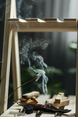 magical smoke from a burning incense stick on an incense stand on a wooden shelf in the interior Concept of mental health, selective focus