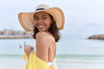 Young african american woman smiling confident wearing summer hat and bikini at beach