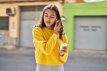 Young african american woman holding earphones at street